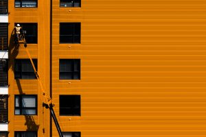 Technicien en nacelle élévatrice intervenant sur la façade d'un immeuble dans le cadre d'une rénovation de copropriété
